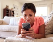 Teenager laying on the couch scrolling on her phone.